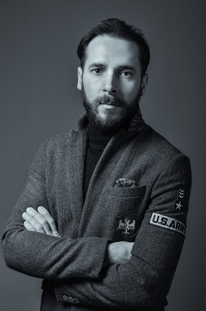 Autoritratto in bianco e nero di Marius Cruceriu, fotografo, indossante una giacca con distintivi militari.