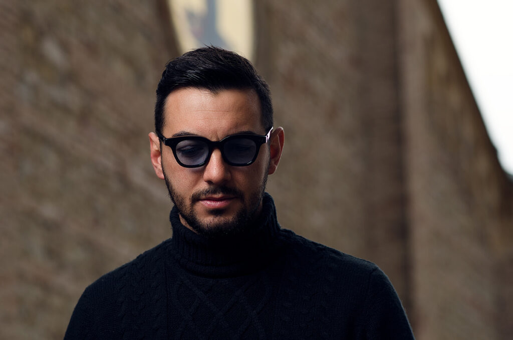 Ritratto uomo con occhiali neri in ambientazione sobria, fotografia moda artigianale