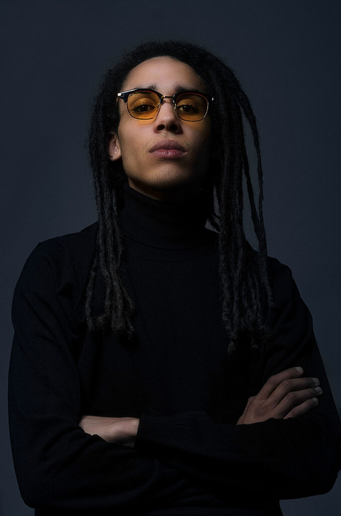 Ritratto maschile con occhiali da sole lenti gialle in studio, stile cinematografico e minimal