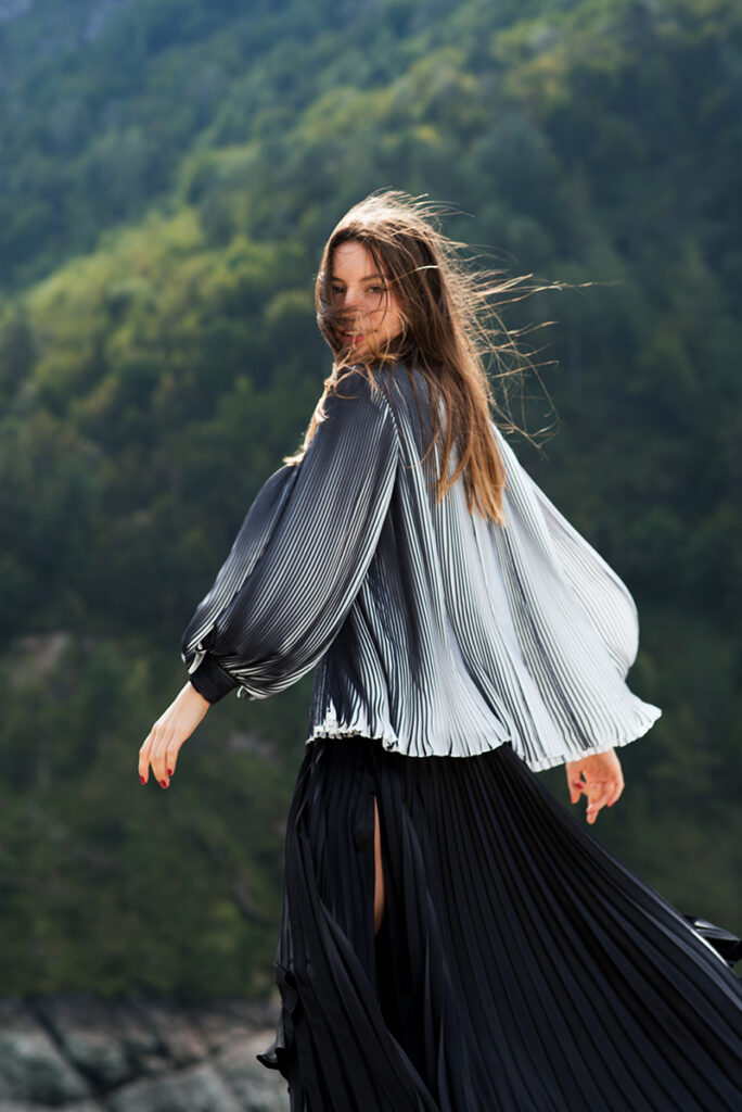 Campagna moda outdoor per Mine de Rien Couture con outfit plissé tra le montagne, scattata da Marius Cruceriu