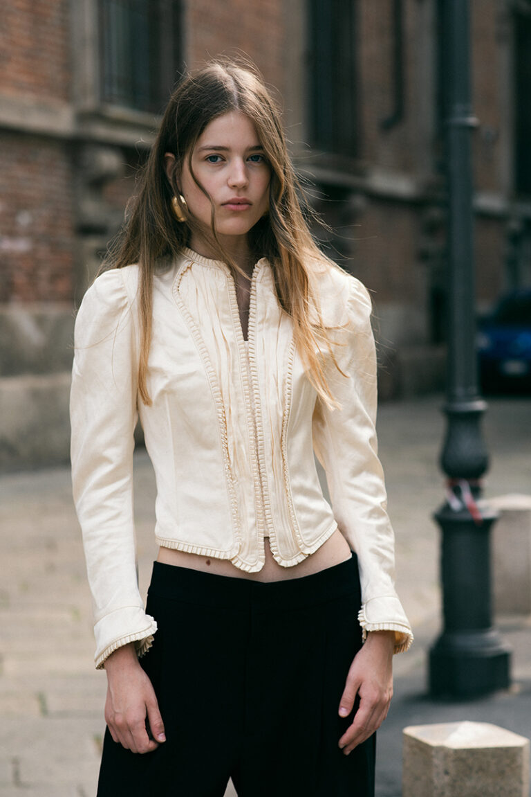 Modella Juta durante un test per Supreme Management Milano, in tre quarti esterno con giacca avorio strutturata e pantaloni neri fluidi, fotografata da Marius Cruceriu in una strada di Milano.