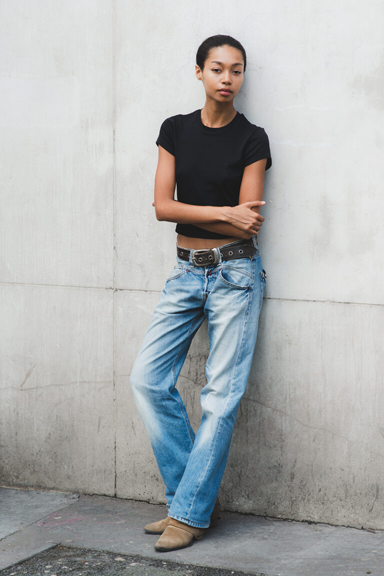 Modella Zoe a Parigi per The Face Paris, ritratto a colori a figura intera appoggiata a un muro, look casual con jeans denim e t-shirt nera, test model realizzato da Marius Cruceriu.
