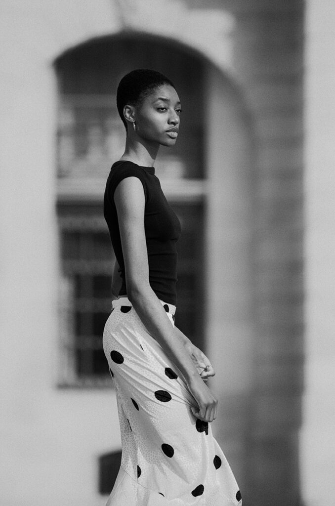 Modella Annaya a Parigi in bianco e nero, profilo con top nero e gonna a pois bianchi, look elegante e fresco per test agenzia The Face, fotografata da Marius Cruceriu.