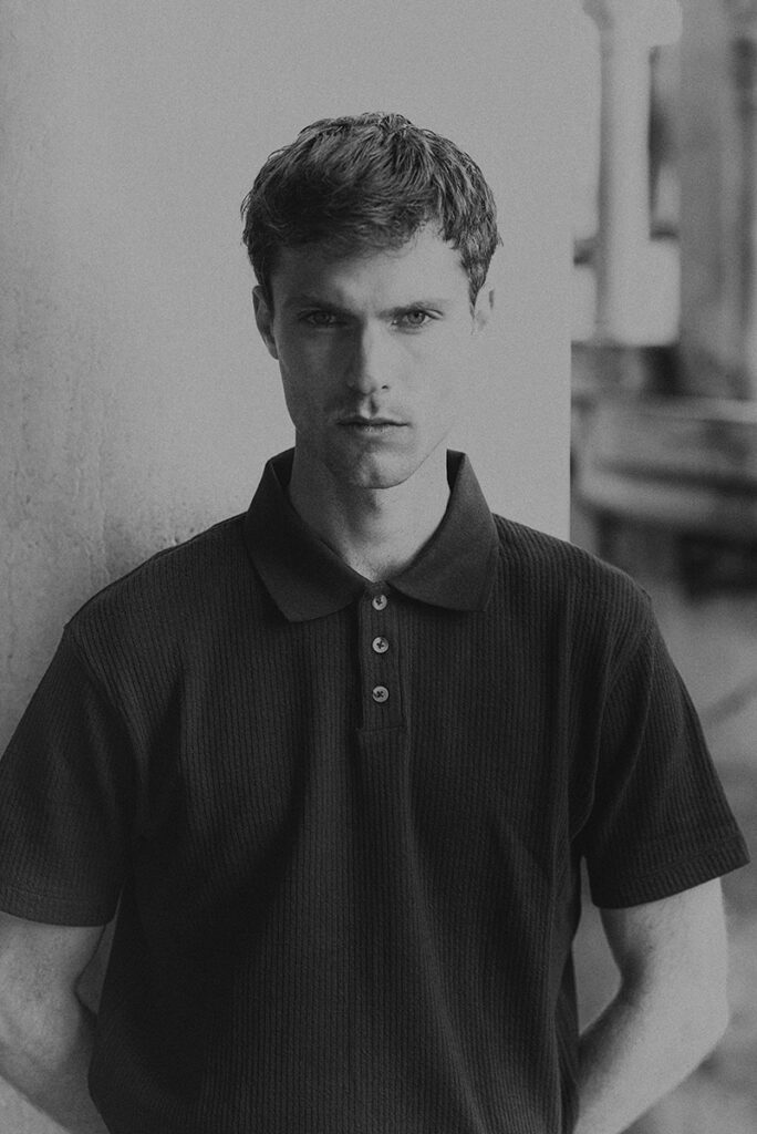 Modello Blake a Venezia in posa frontale con polo nera, ritratto maschile in bianco e nero realizzato da Marius Cruceriu.