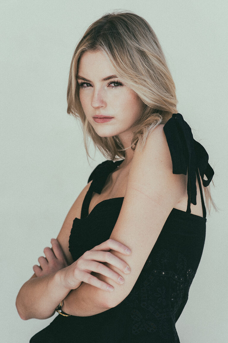 Modella Dalia per Innocence Models Amsterdam ritratta a tre quarti con abito nero e fiocchi sulle spalle, in posa intensa con braccia conserte durante un test a Venezia, fotografata da Marius Cruceriu.