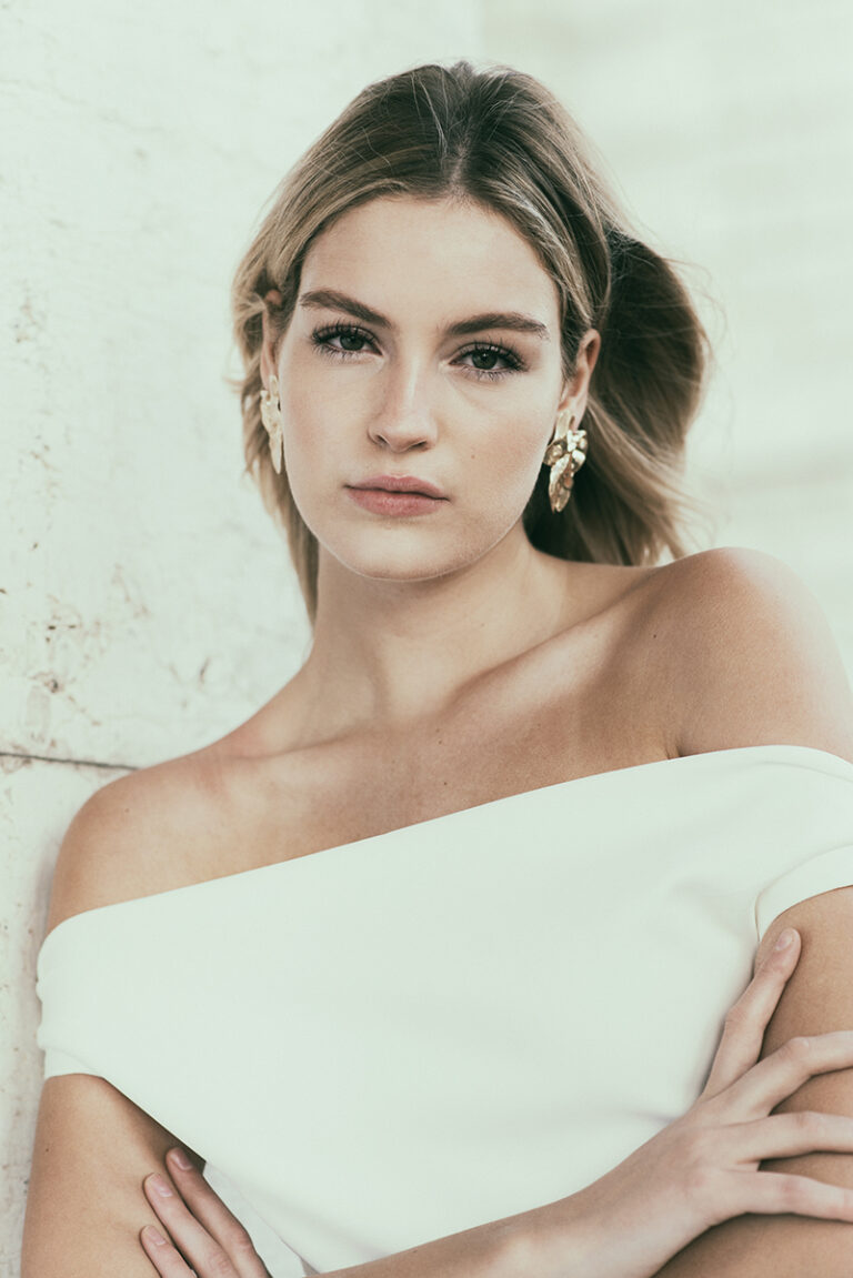 Modella Dalia per Innocence Models Amsterdam ritratta a Venezia da Marius Cruceriu, con abito bianco scollato, maxi orecchini e capelli sciolti mossi dal vento.