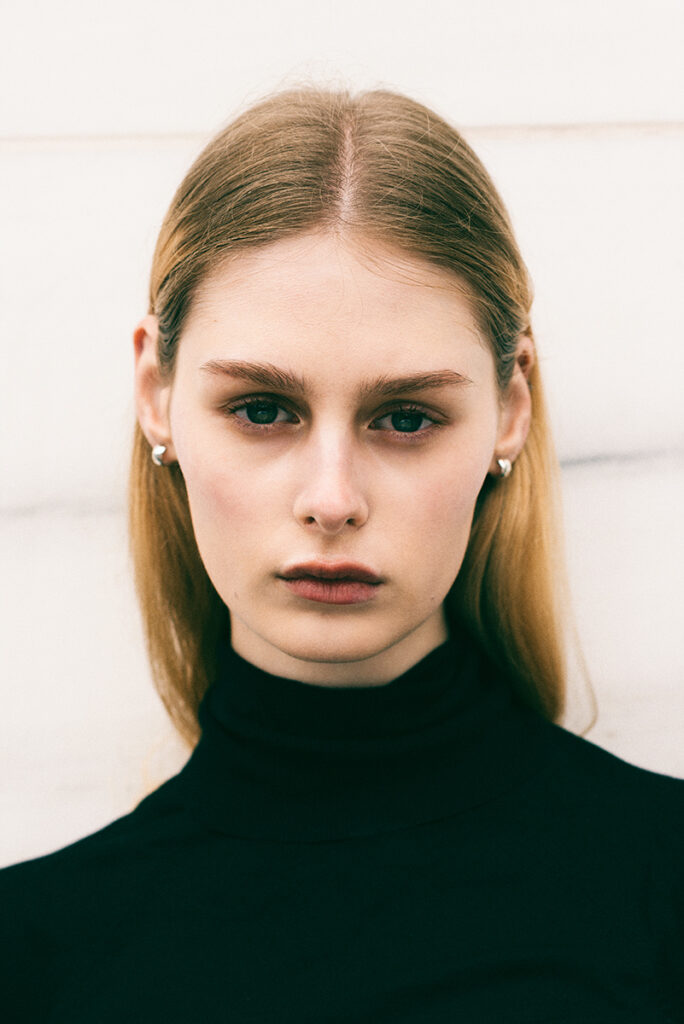 Modella Kornelia a Milano, primo piano intenso con dolcevita nero, sguardo diretto in camera, scatto portrait per agenzia Fabbrica Milano realizzato da Marius Cruceriu.
