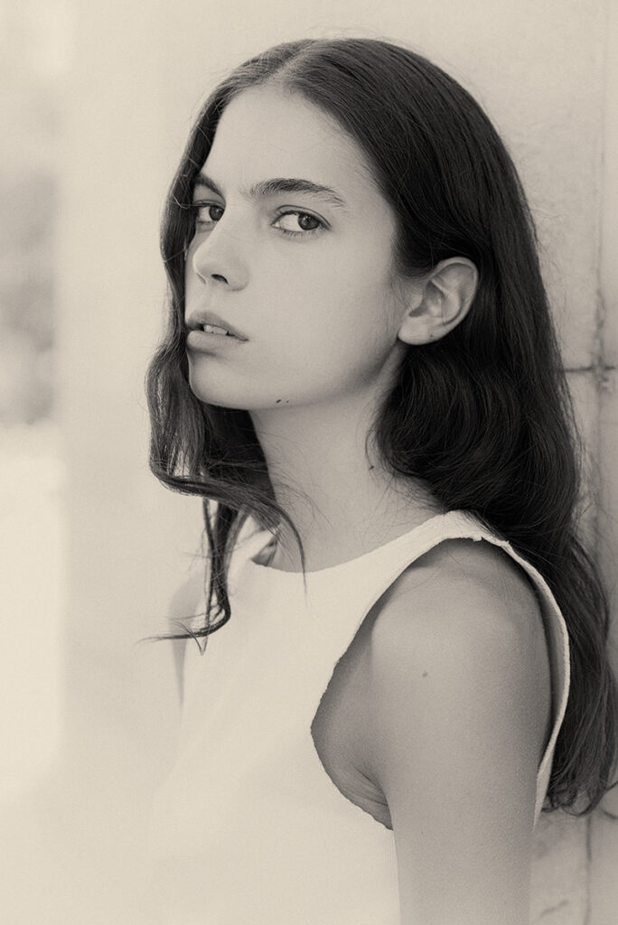 Modella Loli Bahia a Milano in bianco e nero, ritratto di tre quarti con sguardo intenso e capelli sciolti mossi, test model per agenzia Fabbrica Milano, scatto di Marius Cruceriu.