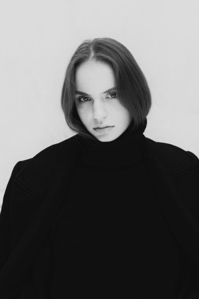 Modella Liddy per Novastars Models, intenso ritratto in bianco e nero con dolcevita nero, sguardo magnetico in camera, test model realizzato da Marius Cruceriu.