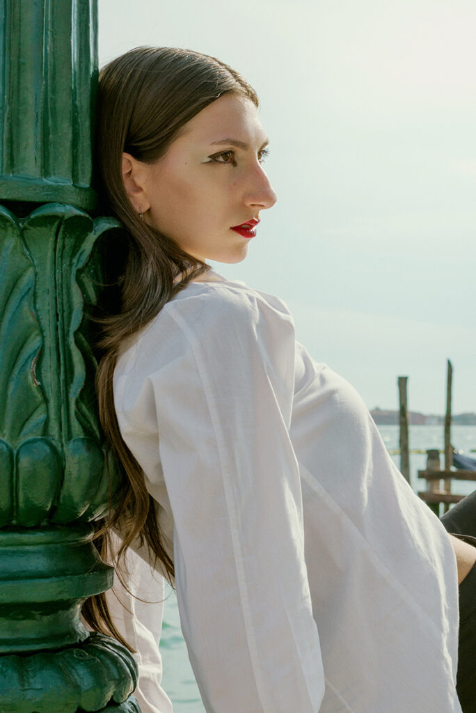 Modella Gloria a Venezia per Iso Model Management, ritratto di profilo a colori con luce naturale, camicia bianca e trucco grafico sugli occhi, test model realizzato da Marius Cruceriu.