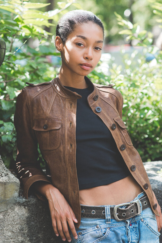 Modella Zoe a Parigi per The Face Paris, ritratto in esterno a luce naturale con giacca in pelle marrone vintage e jeans, sguardo diretto e sicuro, test model realizzato da Marius Cruceriu.