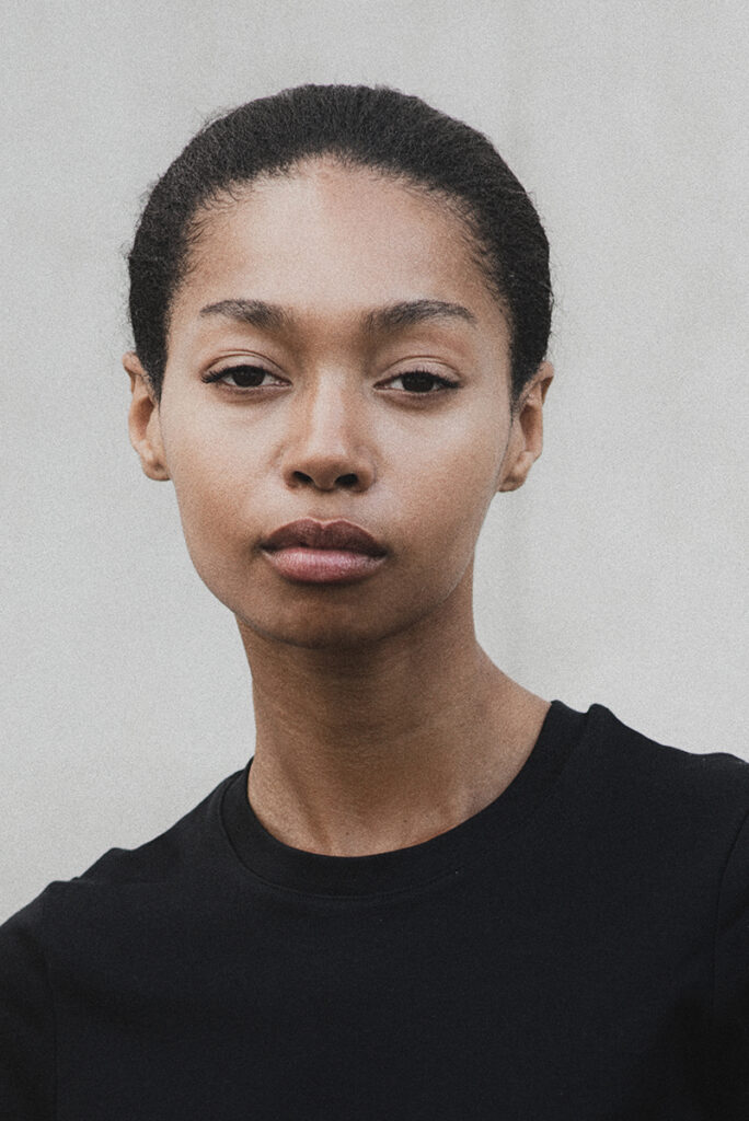 Modella Zoe a Parigi per The Face Paris, ritratto close-up a colori con sguardo intenso e naturale, indossa t-shirt nera, sfondo neutro, test model realizzato da Marius Cruceriu.
