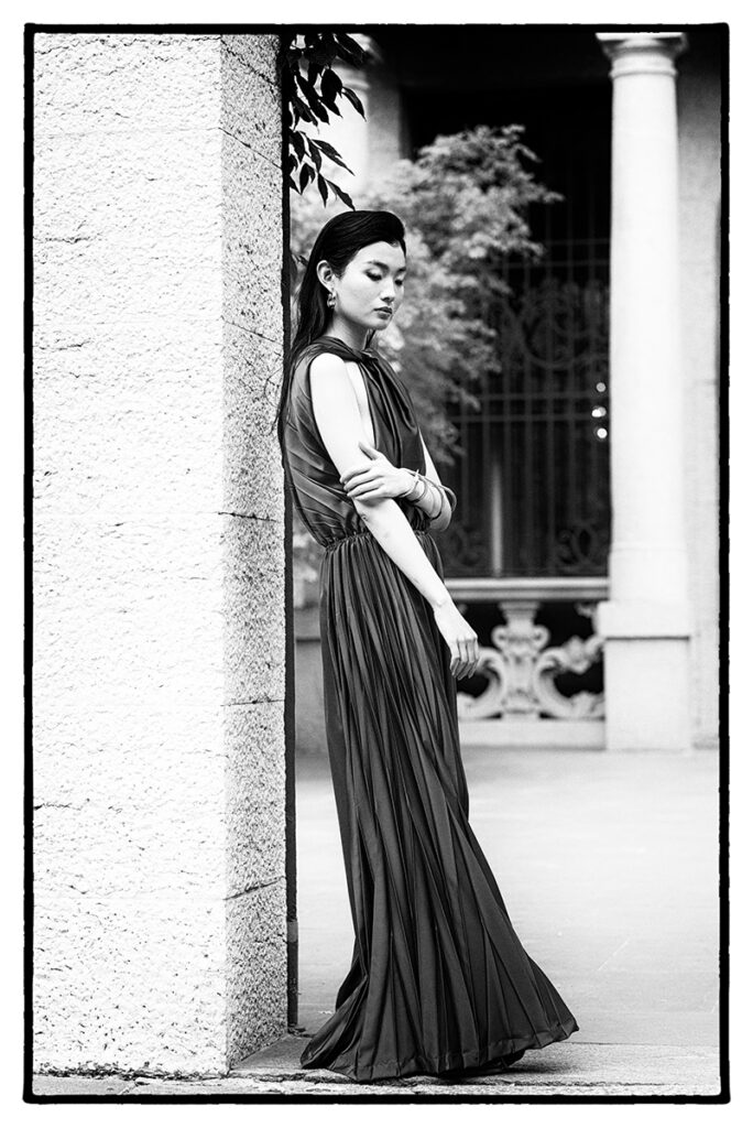 Modella Liu in posa statuaria per l'editoriale "Of Shadows and Silk" pubblicato su L'Officiel Baltic. Indossa un abito lungo plissettato di Mine de Rien Couture. Fotografia e direzione artistica di Marius Cruceriu.